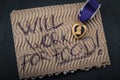 Veterans reintegration and social issues concept with cardboard sign reading Ã¢â¬Åwill work for foodÃ¢â¬Â and a purple heart medal
